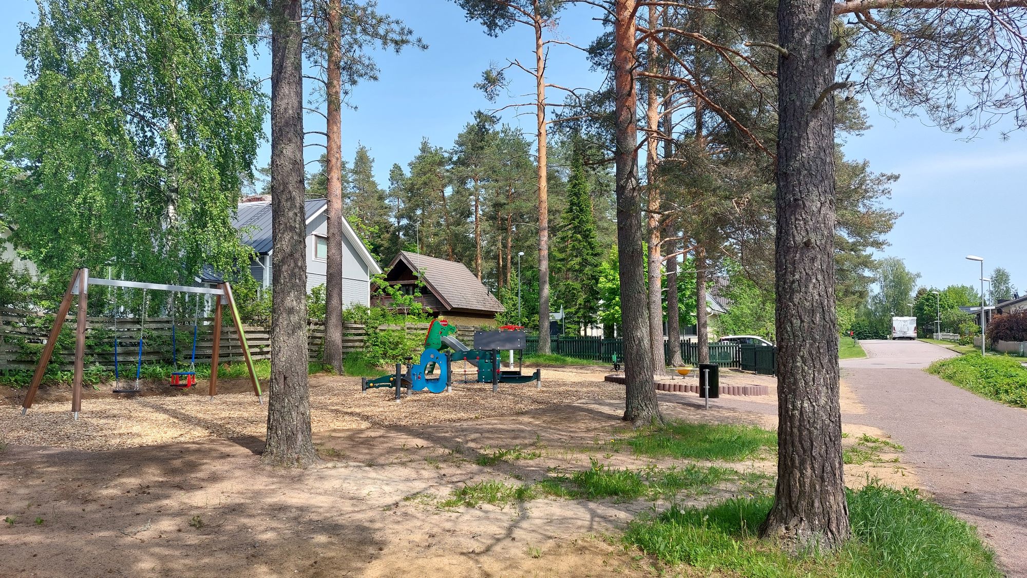 Laihian leikkipaikka, leikkitelineitä, puita, takana taloja.